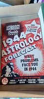 Top view of box containing 1944 Astrology Forecast Annual Guide with prominent red cover and white bold typography featuring horoscope predictions for 1944.