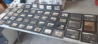 Table displaying over 40 antique cabinet photos and postcards arranged in rows, showing large variety and quantity of items in collection.