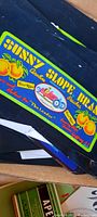 Sunny Slope Brand Peaches fruit crate label showing bold yellow and green color with vintage car logo and fruit illustrations.