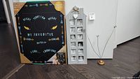 Full view of all three items: boxed baby highlights chalkboard, wooden vertical photo frame for 12 photos, and freestanding wire desktop photo holder with wooden base.
