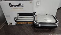 Breville The Perfect Press sandwich maker with box showing product name and key features on packaging.