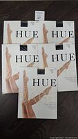 Five packaged pairs of Hue Perfectly Bare Thigh Hi thigh highs in black, showing front of packaging with logo and product name.