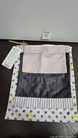 Front view of the small liner bag showing its patterned fabric, mesh pocket, and solid top panel with attached tag.