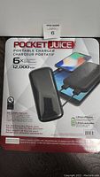 Front of retail packaging showing Pocket Juice portable charger in black, with text detailing capacity, charge capability, and contents.