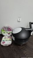 Image showing all items in the lot together including a black and gray salad spinner and two SmartPlanet collapsible meal kits in white lids with utensils attached