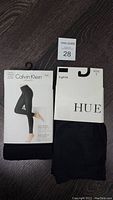 Two packages shown side-by-side on floor: Calvin Klein Ultra Fit leggings and HUE tights in black, new with packaging intact.