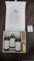 Open white box showing three bottles and two suede care tools inside with UGG branding