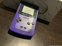 Front angled view of a purple Nintendo Game Boy Color handheld console showing the screen and control buttons.