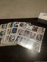 Top-down view of multiple double-sided sheets stacked, showing partial baseball cards in plastic sleeves.