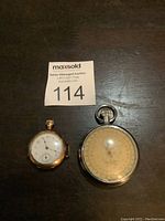 Two watches side by side on dark surface, showing size difference and condition