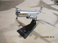 Side-angle view of the silver metallic 1/200 scale Boeing C-97A Stratofreighter model aircraft mounted on a black stand with American flag and text.