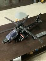 Side view of the large black helicopter toy on a table, showing the main rotor, cockpit, and weapons attachments.