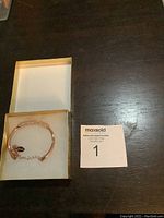 Photo of the Guess copper-tone bracelet with stones in its box, showing the overall bracelet design and packaging.