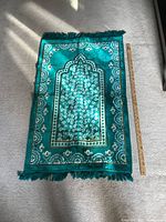 Full view of the green prayer mat with ruler for size reference