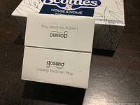 Closed white box labeled 'Gosund Leading the Smart Plug' with a Scotties tissue box in the background.