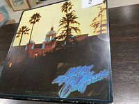 Front cover of Hotel California album by Eagles, showing hotel building with palm trees and neon title text.