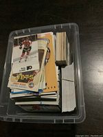 Plastic bin containing a large quantity of hockey cards stacked and bundled with rubber bands, many cards visible showing players in team uniforms.