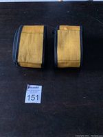 Pair of new moving straps with yellow padded sections and black sides placed side by side on a dark surface.