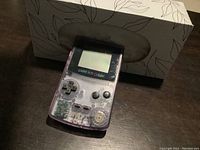 Front view of Nintendo Game Boy Color CGB-001 in transparent purple casing with power on and screen visible.