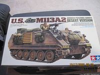 Photo of box for Tamiya 1/35 scale US M113A2 Armored Personnel Carrier Desert Version model kit, with desert camo armored vehicle illustration.