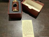 Polemoscope with wood grain finish inside original red box with foam insert and instruction card on dark wooden surface.