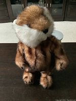 Front-facing view of the plush gopher standing upright on a dark surface, showing its brown and white fur pattern and facial details.