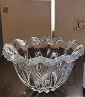 Side view of the clear crystal bowl showing scalloped rim and vertical fluted design with original packaging in background.