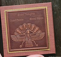 Closed book-style compact travel mirror with embossed winged figure and gold lettering 'Good Thoughts Good Deeds Good Words'. Brown textured cover with gold border.