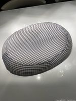 Oval donut-shaped cushion with a plaid cover placed on a white surface, showing the size, shape, and fabric pattern clearly.