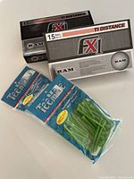 Photo shows two boxes of Grimm FX1 golf balls and two packs of green golf tees.