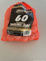 Orange mesh bag containing 60 recycled golf balls with label showing '60 Golf Balls in Value 3dc' and grade 3 variety marking.