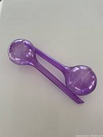 Photo of one purple plastic self-watering bulb device shown on white surface, designed for gradual soil watering.