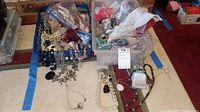 Full view of two containers holding assorted costume jewelry with some pieces spilling out.