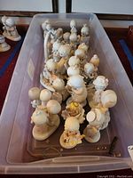 Plastic bin with approximately twenty Precious Moments figurines arranged inside, showing the lot quantity and variety.
