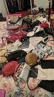 Full view of various purses and bags laid out on bed showing variety of styles and colors including crocheted purses, sequined evening bags, leather and faux leather handbags