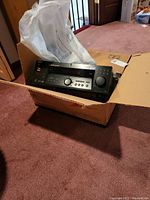 Sony STR-DE675 stereo receiver in retail box on carpeted floor.