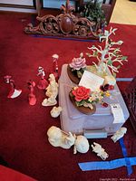 Photo showing group arrangement of snowbabies, Coca-Cola ladies, crystal roses, and Lenox heirloom tree on plastic container and floor