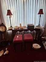 Front view of sofa table with two upholstered stools underneath and various items on top, showing the full furniture pieces.