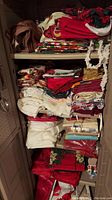 Photo of 4 shelves filled with assorted folded table linens, curtains, holiday linens in various colors and patterns.