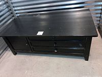 Full side and top view of the black coffee table showing overall shape and drawer configuration.