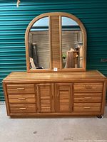 Full front view of the large wooden bureau with the mirror placed on top, showing drawer and door details, natural wood finish, and overall condition.