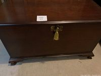 Front view of the closed cherry wood hope chest with tassel key in lock.