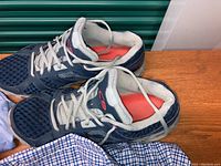 Photo showing pair of men's Champion sneakers in navy blue and grey with orange and grey sole, showing wear and lace-up style.