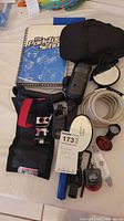 Overview of assorted cycling items including a spiral-bound manual, multi-tools, mirrors, cable lock, and lights arranged on a surface.