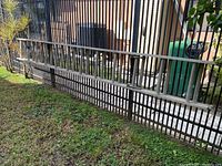 Full length view of a 24-foot aluminum extension ladder laid flat on the ground against a fence, showing its full size and condition.