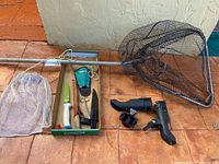 Fishing net, chum bag, fillet cutting utensils including knife sharpener, fillet knife, and scissors photographed together.