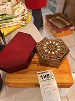Octagonal Tommy Bahamas wood inlaid keepsake box and reddish octagonal box containing blade set placed on a wooden box for size reference