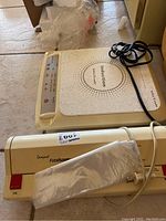 Photo showing Tilia Compact Foodsaver vacuum sealer and VitaCraft induction cooktop together on floor with power cords visible