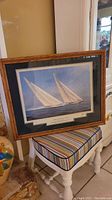 Framed artwork showing two sailboats titled "Yachts of America Cup," signed and double matted under glass with wood frame.