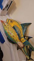 Set of four colorful metal fish wall art pieces arranged to show size and detail.